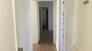 Un couloir aux portes blanches et au plancher en bois, qui mène à une autre pièce.