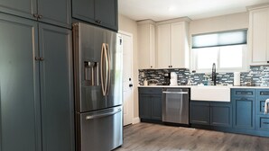 A modern kitchen with dark cabinets, stainless steel appliances, and a tiled backsplash.