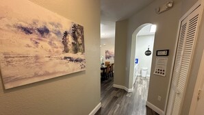 A hallway with a painting of a beach scene, a kitchen area with a sign, and a door with a 'Kitchen' sign. - Windsor Palms 3 bed ground floor condo near DISNEY! (Kissimmee)