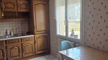 A kitchen with wooden cabinets, a tiled backsplash, a window with a view, and a dining table with chairs.