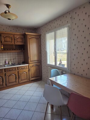 Une cuisine avec des meubles en bois, un pare-feu en carrelage, une fenêtre avec vue et une table à manger avec des chaises.