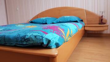 Een bed met een houten frame en een kleurrijke bloemenprint.