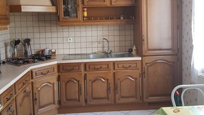 A kitchen with wooden cabinets, a tiled backsplash, a gas stove, and a ceiling light fixture.