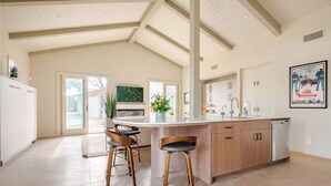 Una cocina amplia con una isla grande, taburetes de madera y un techo alto con vigas a la vista.