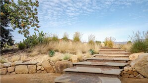 Una escalera de piedra que sube una colina, rodeada de hierba seca y plantas desérticas.