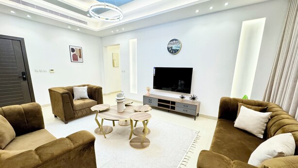 A modern living room with a sofa set, a coffee table, a TV, and a large window.