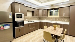 A modern kitchen with built-in appliances, a dining area with a table and chairs, and a tiled backsplash.