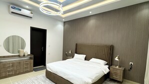 A modern bedroom with a large bed, bedside tables, a mirror, and a ceiling light fixture.