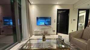 Ein modernes Wohnzimmer mit einem Glastisch, einem an der Wand montierten Flachbildfernseher und einem beigen Sofa.
