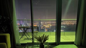 Ein modernes Wohnzimmer mit großem Fenster und Blick auf nächtliche Stadtansicht.