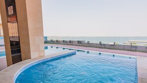 Ein Pool mit Meerblick, umgeben von Liegestühlen und einem Rettungsschwimmer-Schild.