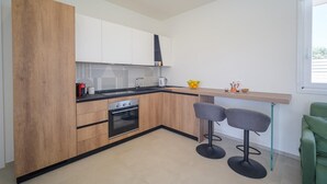 Une cuisine moderne avec des meubles en bois, un plan de travail noir, un four encastré et deux tabourets de bar.