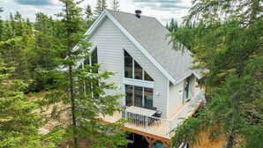 A modern two-story cabin with a large deck, surrounded by dense forest. - Private Lakefront Chalet with Spa, Arcade & Retro Vibes (Shannon)
