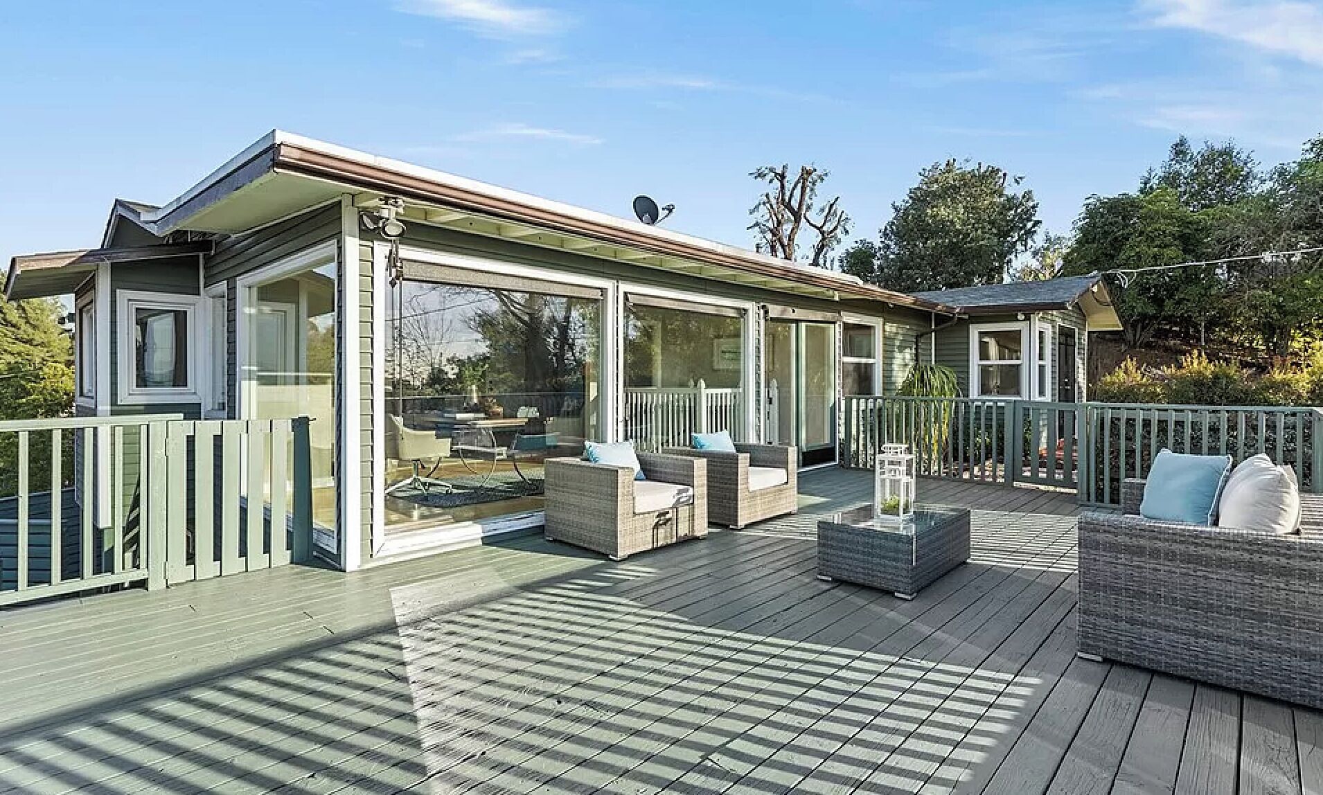 A covered deck with outdoor furniture, glass doors, and a wooden railing.
