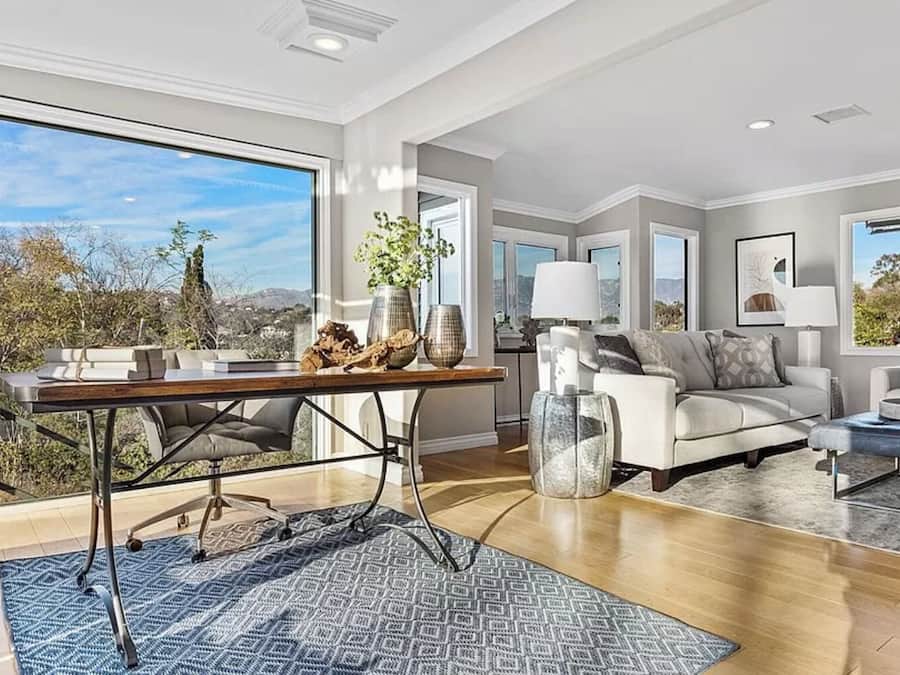 A spacious living room with a large window, a wooden coffee table, a sofa, and a dining area with a table and chairs.