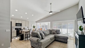 A modern living space with a kitchen, dining area, and a grey sectional sofa. - Kimberly Surprise (Surprise)