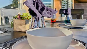 A dining table with a bowl and plates, a potted plant, and a window with shutters. - Kimberly Surprise (Surprise)