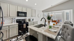 A modern kitchen with white cabinets, a black stove, a microwave, and a sink. - Kimberly Surprise (Surprise)
