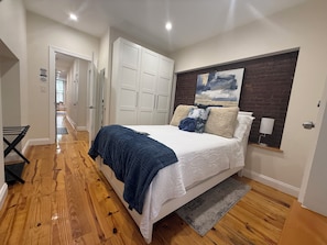 A bedroom with a bed, a wardrobe, a painting, and a lamp.