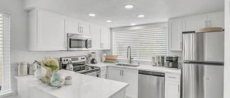 A modern kitchen with white cabinetry, stainless steel appliances, and a central island.
