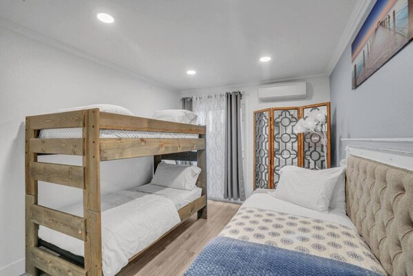 Ein Schlafzimmer mit Etagenbett, einem Einzelbett und einem dekorativen Raumteiler.