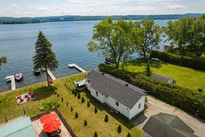 A lakeside property with a house, a hot tub, and a dock with boats.