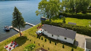 Una proprietà sul lago con una casa, un pontile e una vasca idromassaggio.