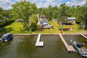 Una propiedad frente al lago con un muelle, una casa con terraza y un bote.