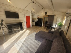 A cozy living room with a fireplace, a sofa, a dining area, and a kitchen.