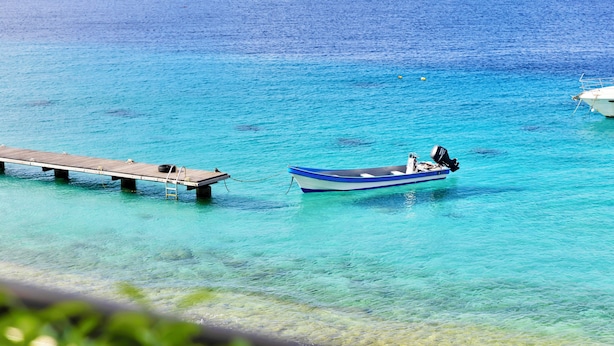 A boat docked at a pier extending into clear turquoise waters.