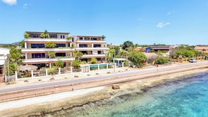 A beachfront hotel with multiple floors, a pool, and a beachside road.