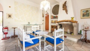 Una habitación acogedora con una cama blanca, almohadas azules, una mesa redonda y una chimenea.