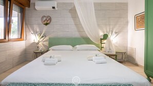 Habitación de hotel con una cama grande, dos mesitas de noche, un cabecero verde, un aire acondicionado de pared y un adorno en forma de corazón en la pared.