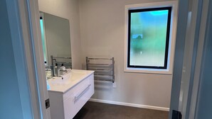 Un baño moderno con tocador blanco, un perchero y una ventana con vistas.