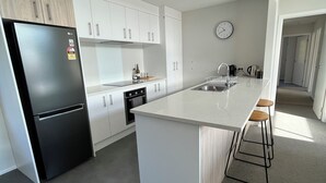Una cocina moderna con una isla grande, armarios blancos y un refrigerador negro.