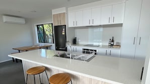 Una cocina moderna con una isla grande, armarios blancos y dos taburetes de madera.
