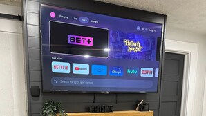 Pared de entretenimiento moderna con un televisor montado que muestra diferentes servicios de transmisión.