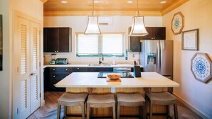 A kitchen with a central island, wooden ceiling, and pendant lights. - YellowBird Estate in Double Bay - Fully Staffed! (North Palmetto Point)