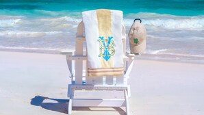 A beach chair with a towel and a bag on a sandy beach with clear blue water and a distant island. - YellowBird Estate in Double Bay - Fully Staffed! (North Palmetto Point)