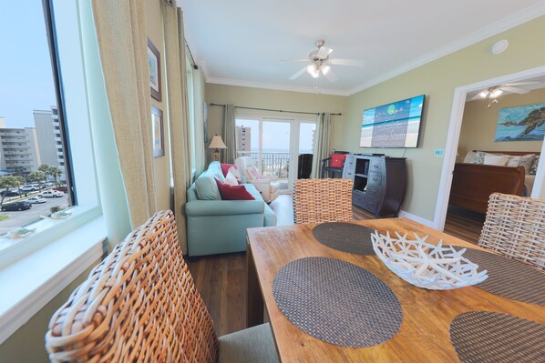 Un salon moderne avec une table à manger en bois, des chaises en osier, un canapé et un téléviseur.
