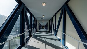 A corridor with large windows and metal railings, leading to a distant exit. - Crystal Tower Corner w/ 2 Balconies, 3 Pools, Lazy River, Free Daily Activities (Gulf Shores)