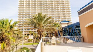 A high-rise hotel with multiple balconies, palm trees, and a blue structure with a truss design. - Crystal Tower Corner w/ 2 Balconies, 3 Pools, Lazy River, Free Daily Activities (Gulf Shores)