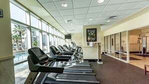 A gym with treadmills aligned along a wall with large windows, a water fountain, and exercise equipment. - Crystal Tower Corner w/ 2 Balconies, 3 Pools, Lazy River, Free Daily Activities (Gulf Shores)
