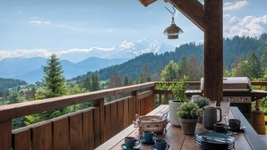 A wooden deck with a table set for tea, a grill, and a view of snow-capped mountains. - Chalet K1027 - mountain stay 14p spa and Mont Blanc views - OVO Network (Cordon)