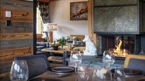 A cozy interior with a fireplace, wooden walls, and a dining area with wine glasses. - Chalet K1027 - mountain stay 14p spa and Mont Blanc views - OVO Network (Cordon)