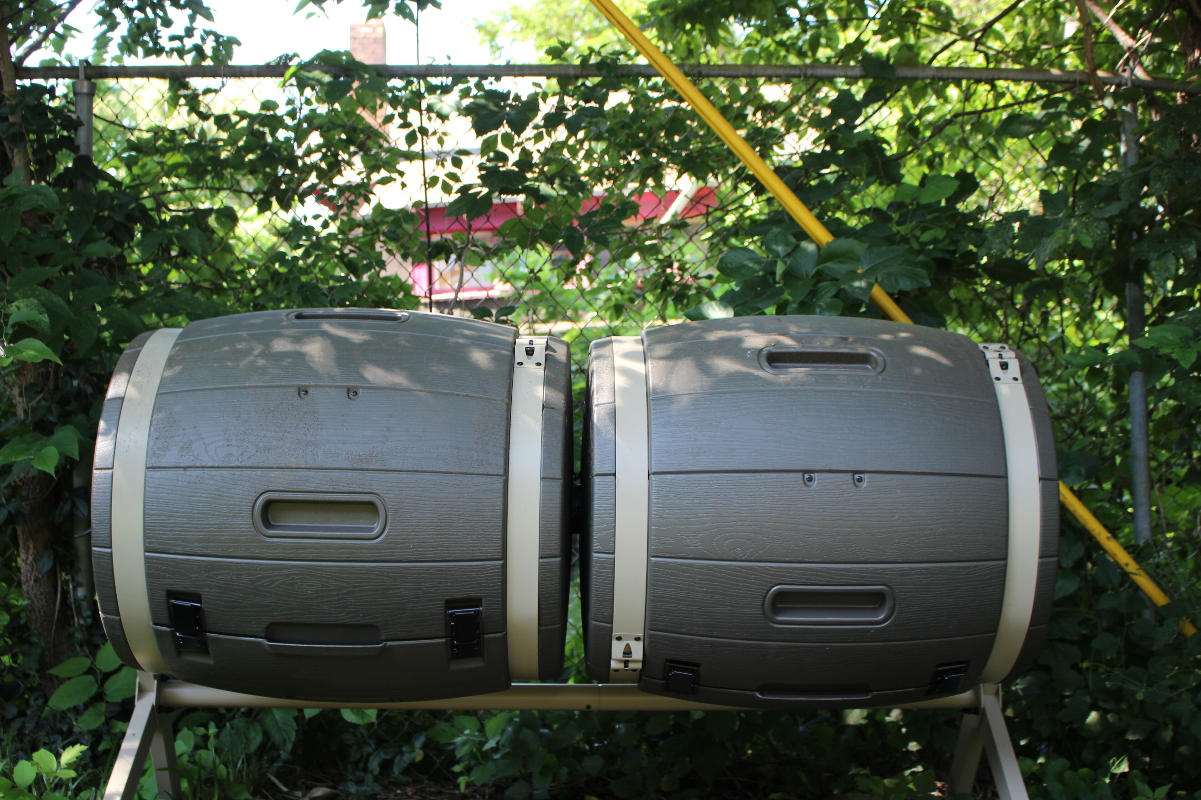 Twee cilindrische speakers gemonteerd op een standaard met metalen frame, omringd door groen en een gele paal.