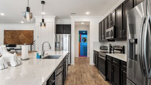 A modern kitchen with stainless steel appliances, a marble countertop, and a wooden floor.