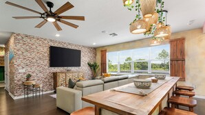 A modern kitchen with a brick wall, wooden ceiling fan, and hanging wicker light fixtures.