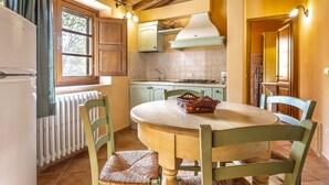 Une cuisine avec une table ronde, des chaises, une fenêtre, des placards et un radiateur.