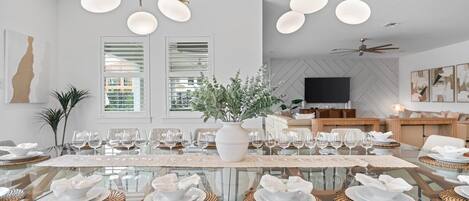 A modern dining area with a glass table, white plates, and woven placemats.